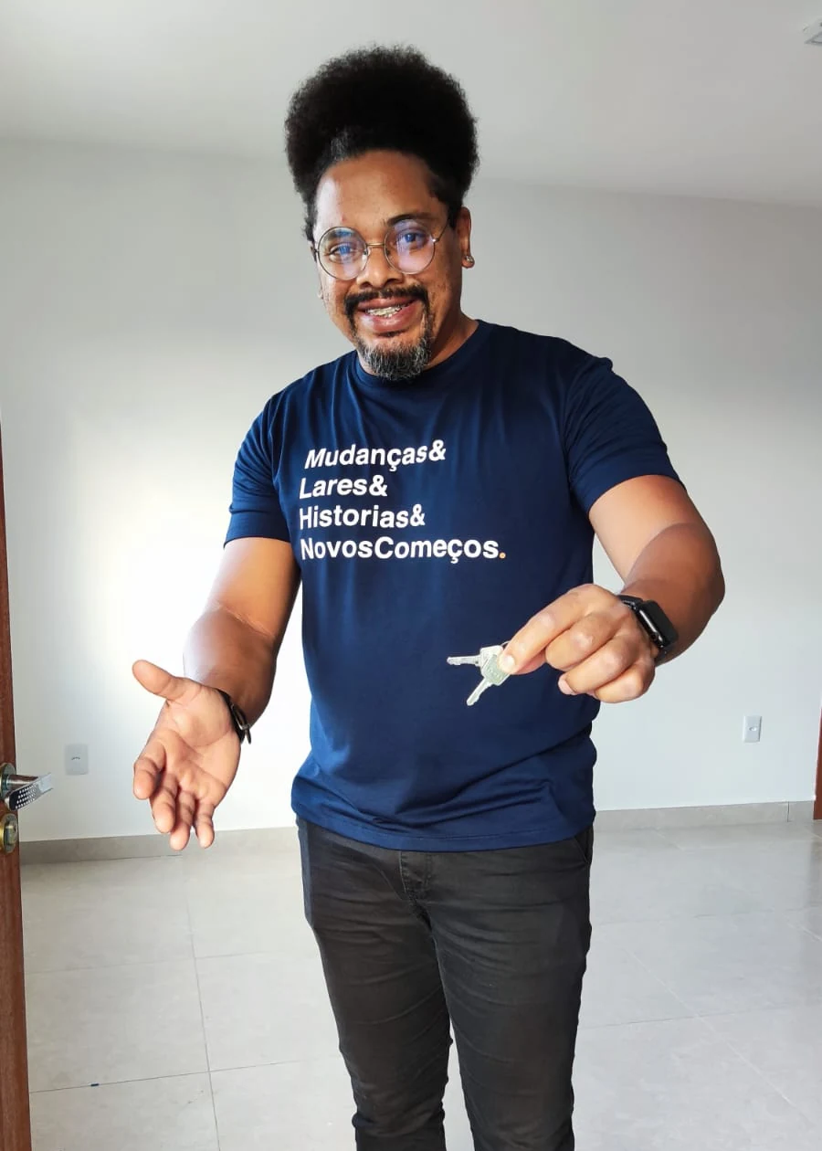 Wellington Gomes sorrindo e segurando um par de chaves dentro de um apartamento vazio